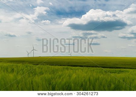 Wind Turbines Situated In A Green Wheat Field