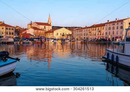 Izola, Slovenia - May 1, 2019: Scenic Harbour With Boats And Brightly Coloured Houses On The Sunset 