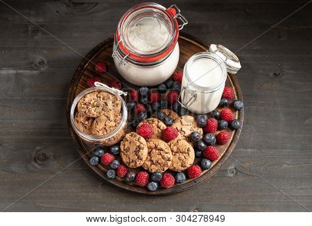 Biscuits, Raspberries, Blueberries, Milk, Flours Jars Over Rounded Wooden Platter.