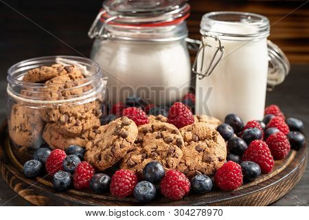 Biscuits, Milk, Flour Recipients And Forest Fruits Placed On Rounded Wooden Platter Close-up.