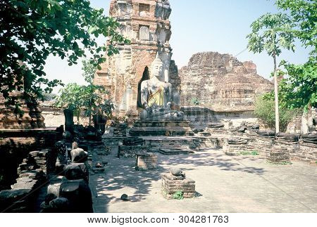 A Sculpture Of The Buddha Sits Among The Ancient Ruins Of Wat Phra Mahathat In Ayutthaya, Thailand.