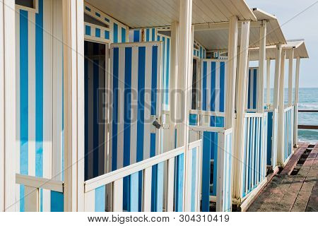 Striped White And Blue Striped Beach Houses And Black Sandy Beach, Tyrrhenian Sea Near Roma, Italy