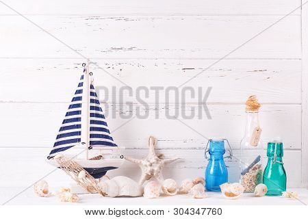 Marine Decorations Near By Wooden White  Wall. Decorative Boat Or Ship, Star Fish, Shells, Blue Bott