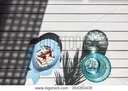 Blue Glass Of Clean Water And Pills On White Wooden Background With Shadows From Sunlight. Concept F
