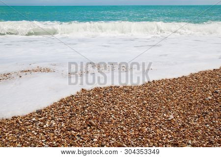 Beautiful Wild Beach With Azure Sea, Waves With White Foam And Pebbles On The Shore In Gargano, Ital