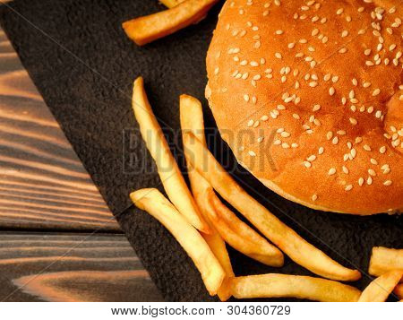 Traditional Hamburger And French Fries On A Black Napkin.