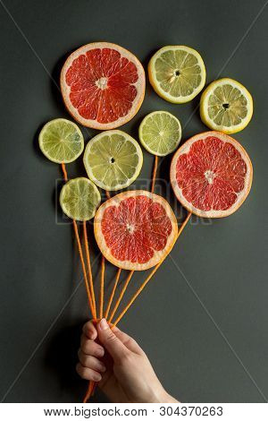 A Female Hand Holds Air Balloons With Orange Threads Made Of Citrus Slices (lemon, Lime, Orange, Gra