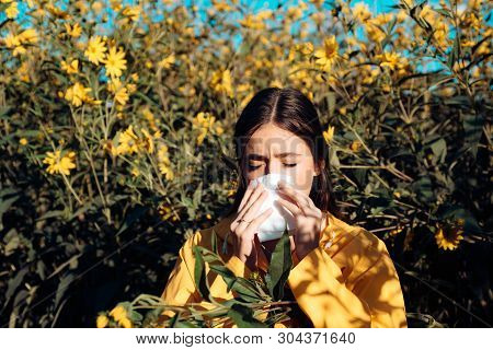 Woman Is Blowing Her Nose Near Flowers In Bloom. Young Girl Sneezing And Holding Paper Tissue In One