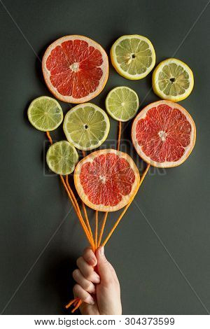 A Female Hand Holds Air Balloons With Orange Threads Made Of Citrus Slices (lemon, Lime, Orange, Gra
