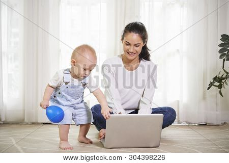 Freelance Woman Working On Laptop When Her Little Son Interferring And Trying To Close The Lid