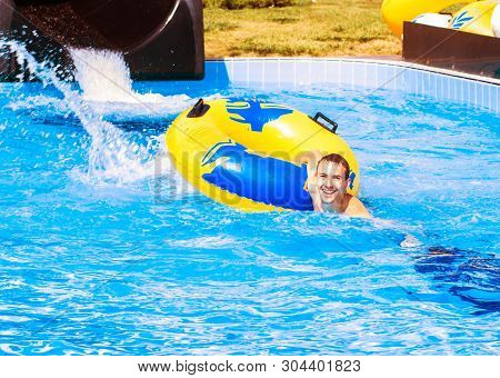Funny Excited Man Enjoying Summer Vacation In Water Park Riding Yellow Float Laughing.