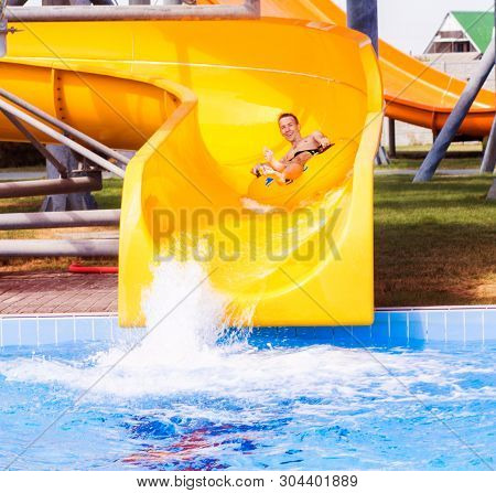 Funny Excited Man Enjoying Summer Vacation In Water Park Riding Yellow Float Laughing.