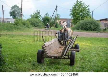 Litynia Village, Ukraine - June 02, 2018: Two Young Boys Riding On An Old Wooden Cart. Life In A Vil