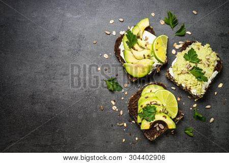 Sandwiches With Avocado And Cream Cheese With Grain Bread And Seeds. Black Slate Background, Top Vie