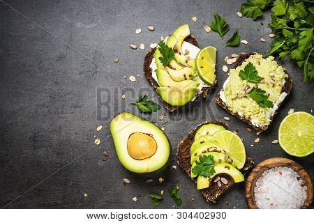 Sandwiches With Avocado And Cream Cheese With Grain Bread And Seeds. Black Slate Background, Top Vie