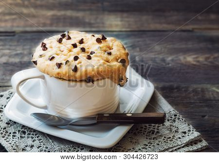 Fresh Homemade Cake In Mug With Peanut Butter And Chocolate Chips On Rustic Wooden Background. Cooke