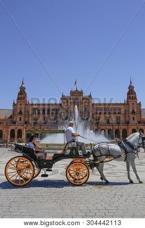 Seville, Spain - July 7th, 2018: Carriage Driver Braking In Front Of Plaza De Espana Fountain, Sevil