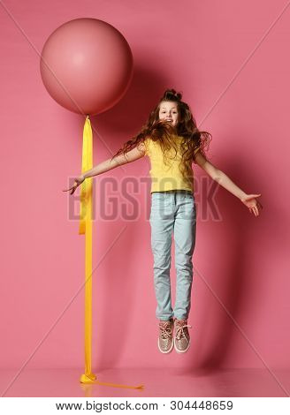 Smiling Young Teen Girl In Blue Jeans And Yellow T-shirt With Her Hands Spread Flying Up The Same As