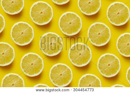 Fresh sliced lemon on yellow background. Creative pattern made of lemon.