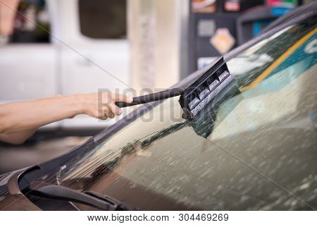 Close-up Of A Girls Hands With A Car Windshield Cleaning Brush From Insects. Independent Washing Of 