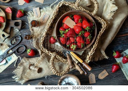 Overhead Shot Of Tasty Ripe Strawberries In Wooden Bowl Stands In Wicker Strawy Basket On Rustic Tab