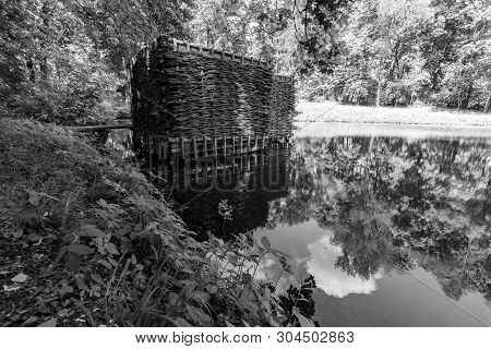 Wooden Building On The Shore Of The Pond. Wicker Building In The Forest.