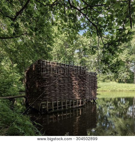 Wooden Building On The Shore Of The Pond. Wicker Building In The Forest.