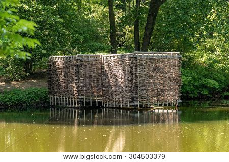 Wooden Building On The Shore Of The Pond. Wicker Building In The Forest.