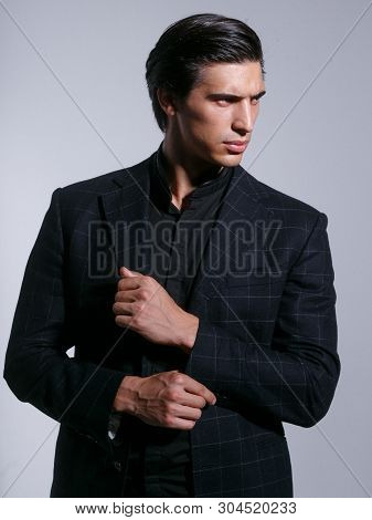 Close Up Of A Brutal Man In Elegant Suit, Poses With Attitudine, Looking In Profile, Isolated In A W