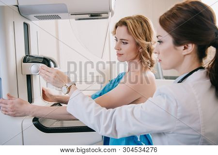 Attentive Radiographer Adjusting X-ray Machine For Mammography Test While Standing Near Patient