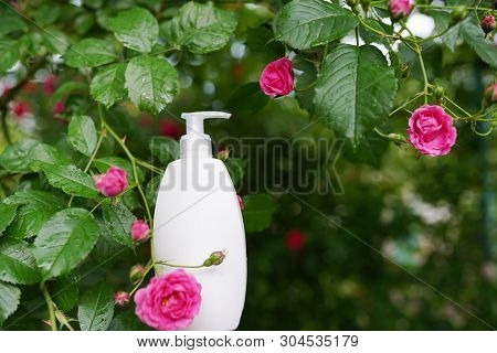 Cleanser Cosmetic. White Bottle On Nature Flowers Background With Copy Space. Body Face Care , Mock-