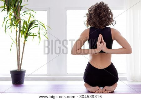 Young Slender Female Is Standing At Bridge Pose. Athletic Brunette Woman In Black Uniform Is Practic
