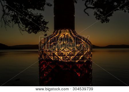 Beautiful Rum Bottle Full With Rum Holding In Front Of A Sunset Over Watson Taylors Lake At Crowdy B