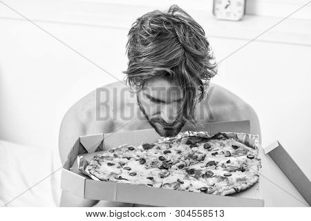 Food Delivery Service. Portrait Of Lazy Muscular Man Eating Pizza While Laying On A Bed At Home. Man