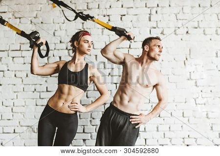 Athletic Man And Woman Doing Trx Workout At Gym. Health And Fitnes Concept.