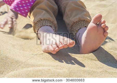 Bare Children's Feet On The Beach. Close-up