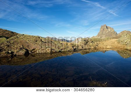 Midi Dossau Peak reflected in a lake. Ossau Valley, Pyrenees National Park, Pyrenees, France.