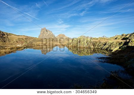 Midi Dossau Peak reflected in a lake. Ossau Valley, Pyrenees National Park, Pyrenees, France.