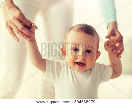 family, child, childhood and parenthood concept - happy little baby learning to walk with mother help at home