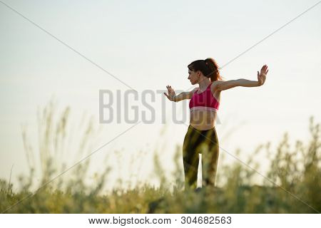 Young Woman Doing Stretching Outdoor. Warm up Exercise in the Hot Summer Evening. Sport and Healthy Active Lifesyle Concept.