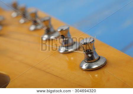 Musical Instrument - Fragment Headstock Peghead Neck Tuning Peg Electric Guitar On A Blue Wood Backg