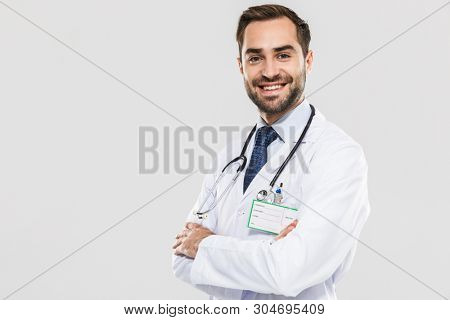 Portrait of cheerful young medical doctor with stethoscope smiling at camera and standing wth arms crossed isolated over white background