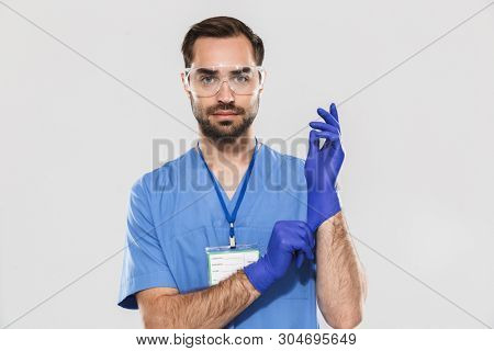 Portrait of caucasian young medical specialist working in hospital and wearing disposable sterile gloves isolated over white background