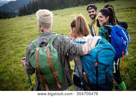 Gorup Of Friends Climbing Up Hill, With Backpacks And Climbing Stick