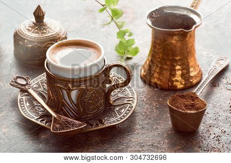 Oriental Coffee Cooked In Traditional Turkish Copper Coffee Pot Poured In A Cup On A Dark Table