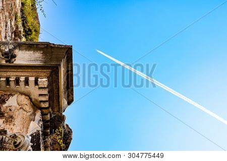 The Plane Leaving A Condensation Trail Flies High Above The Gates Of Hadrian. Adrian Gate, Antalya L