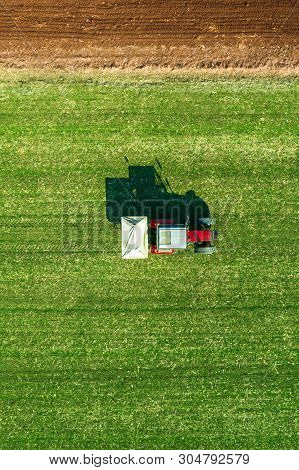 Agricultural Tractor Is Fertilizing Wheat Crop Field With Npk Fertilizers, Aerial View From Drone Po