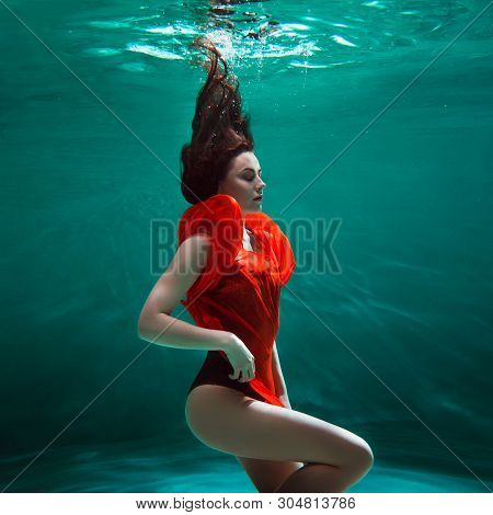 Mystical Underwater Portrait Of A Beautiful Young Woman In A Orange Dress. Girl Swimming Underwater,