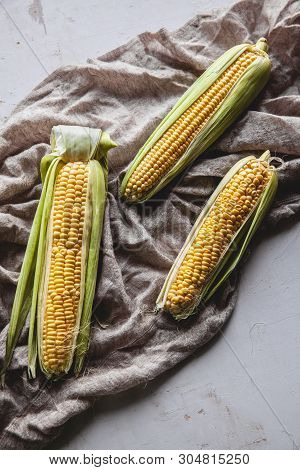 Raw Corns Freshly Picked With Green Cornhusk On Rustic Table Vintage Background Top View A