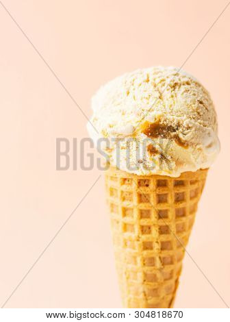 Scoop Of Delicious Salted Caramel Toffee Vanilla Ice Cream In Waffle Cone On Pastel Peachy Pink Back